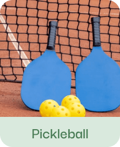 Blue pickleball paddles and yellow ball against brick wall